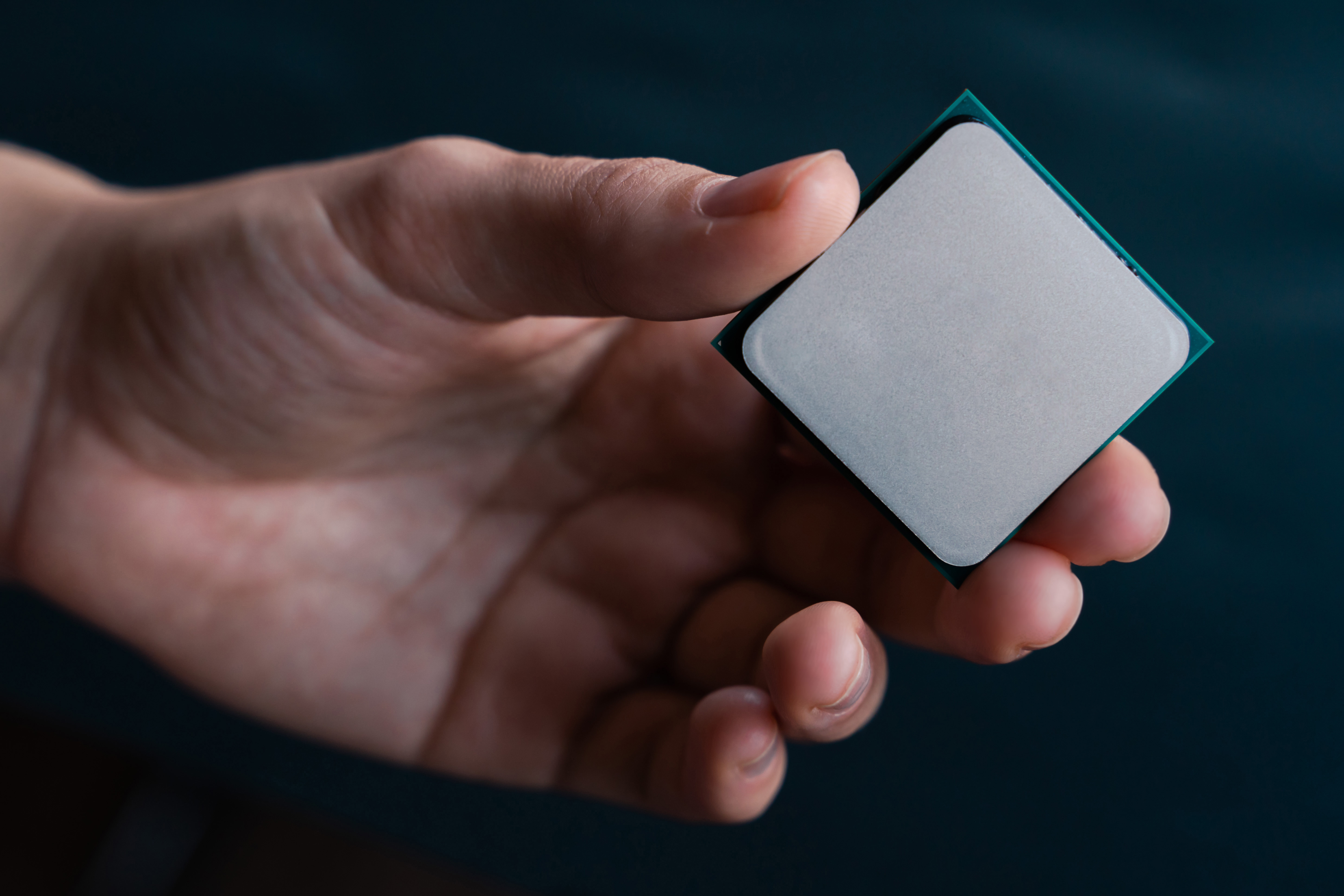 Intel or AMD - Image of hand holding silver computer processor.