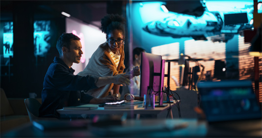 Two people working at a computer in a futuristic setting.